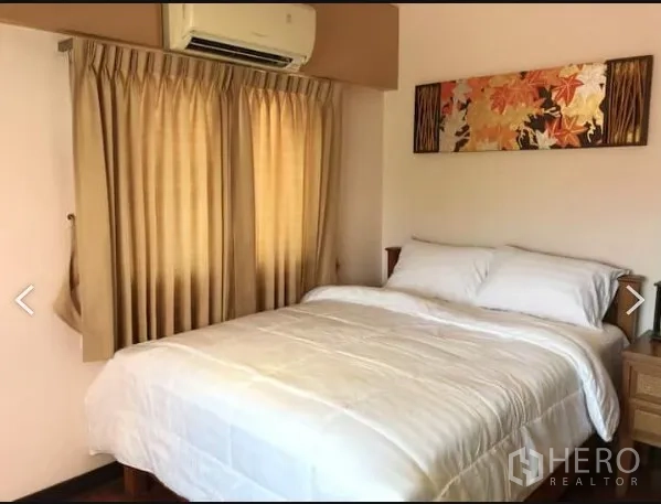 Detached House for sale in Saphan Sung, Bangkok - Cozy bedroom with double bed, beige curtains and wall art under an air conditioner.