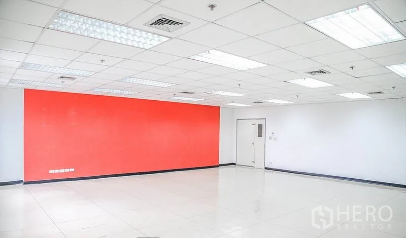 办公空间 出租在Bang Na, Bangkok - 大型办公室内景，面对红色强调墙，荧光灯照明。