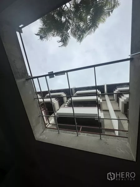 Townhouse for rent or sale in Suan Luang, Bangkok - Skylight view up to the low‑rise building facade and tree canopy.