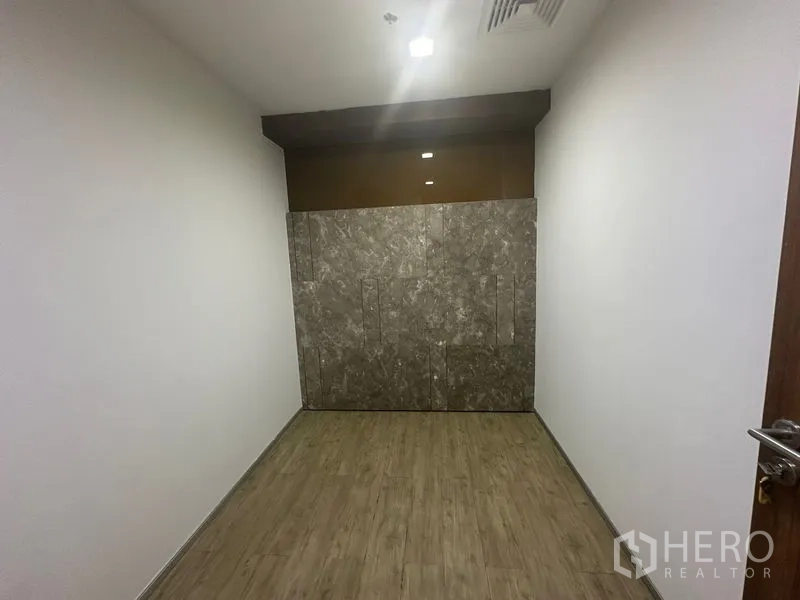 Office Space for rent in Khlong Toei, Bangkok - Compact storage or server room with wood floors and a stone accent wall.