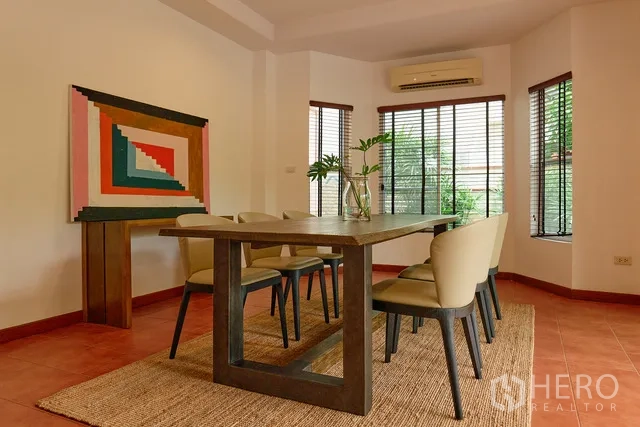 Detached House for rent in Watthana, Bangkok - Corner dining room with windows, air conditioner, wooden table and six chairs.