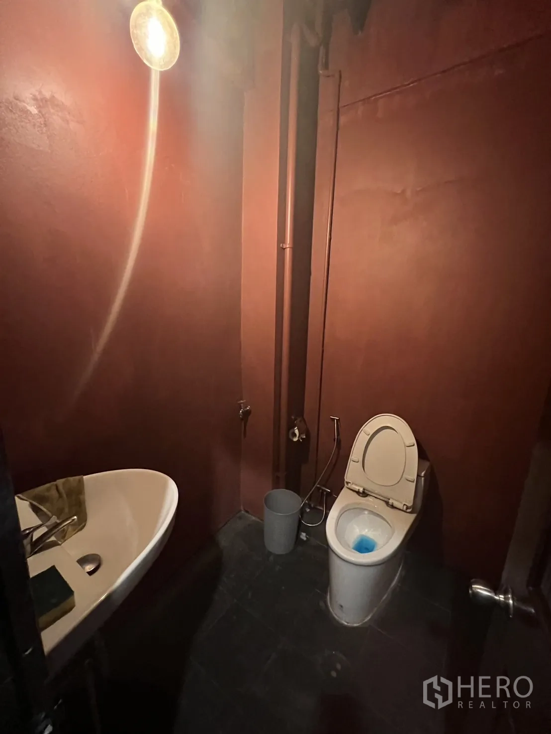 Shophouse for rent in Watthana, Bangkok - Restroom with maroon walls, toilet and corner basin.