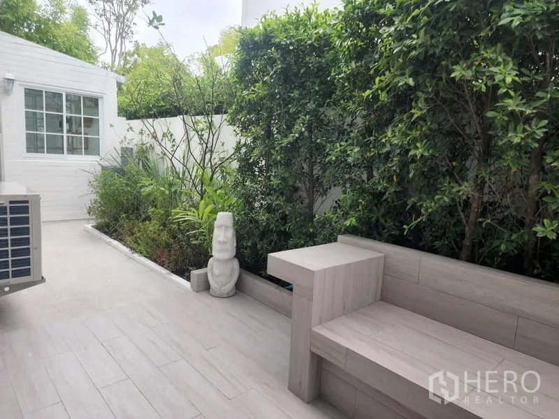 Detached House for rent in Bang Phli, Samut Prakan - Private garden corner with built‑in bench, lush plants and a small white outbuilding.