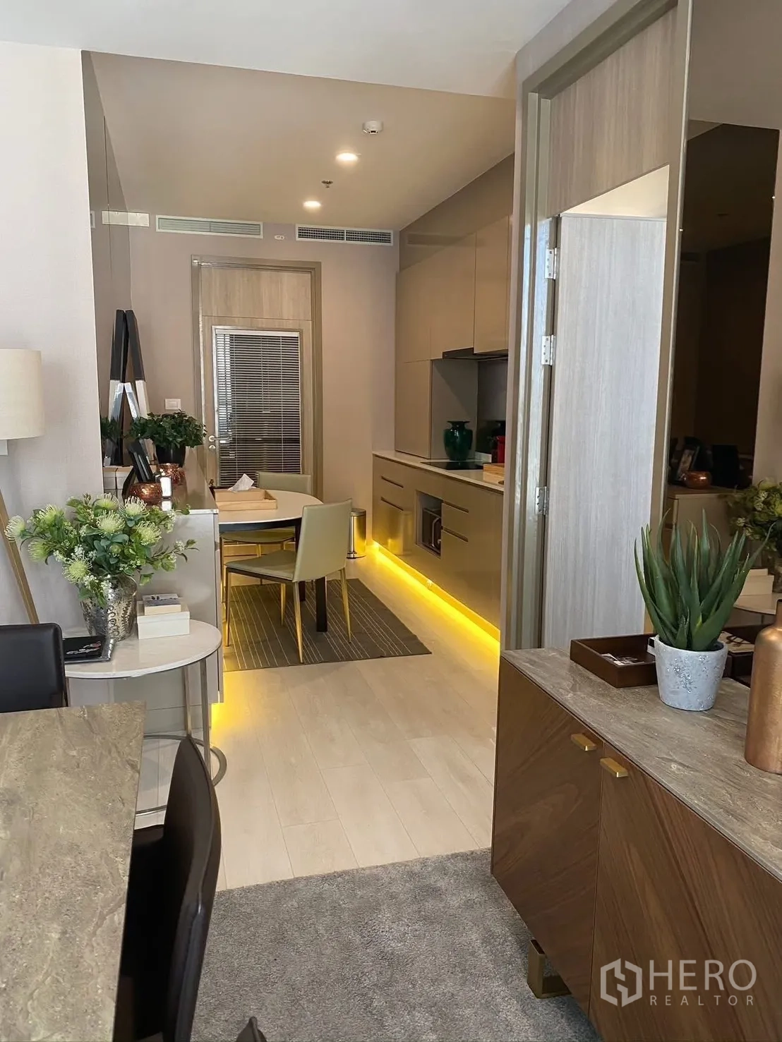 公寓 for rent in Pathum Wan, Bangkok - 从客厅望向厨房的开放格局，浅木地板与氛围灯带。