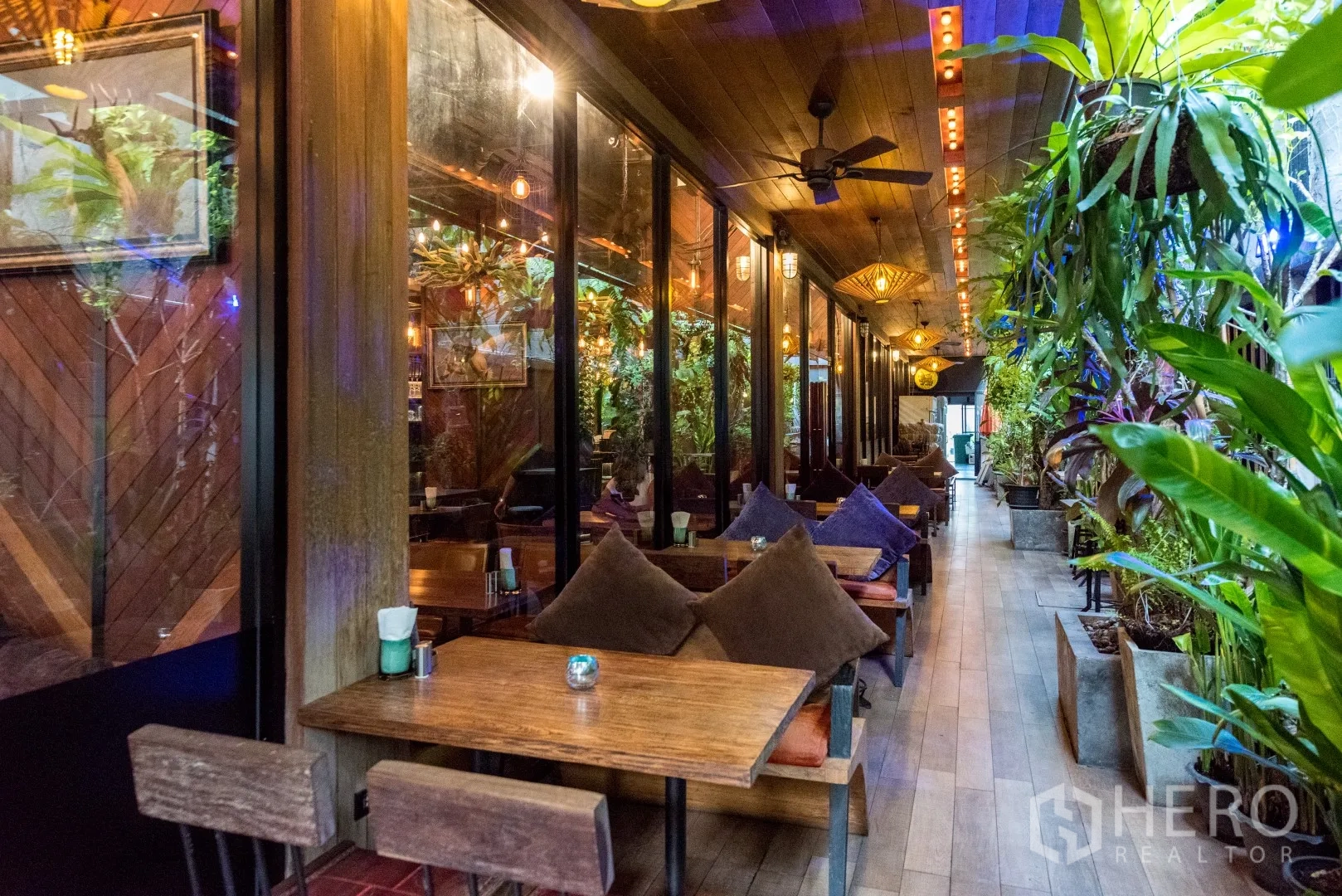 Retail Space for rent in Watthana, Bangkok - Covered terrace seating with wooden tables, cushions, ceiling fans, and lush plants.