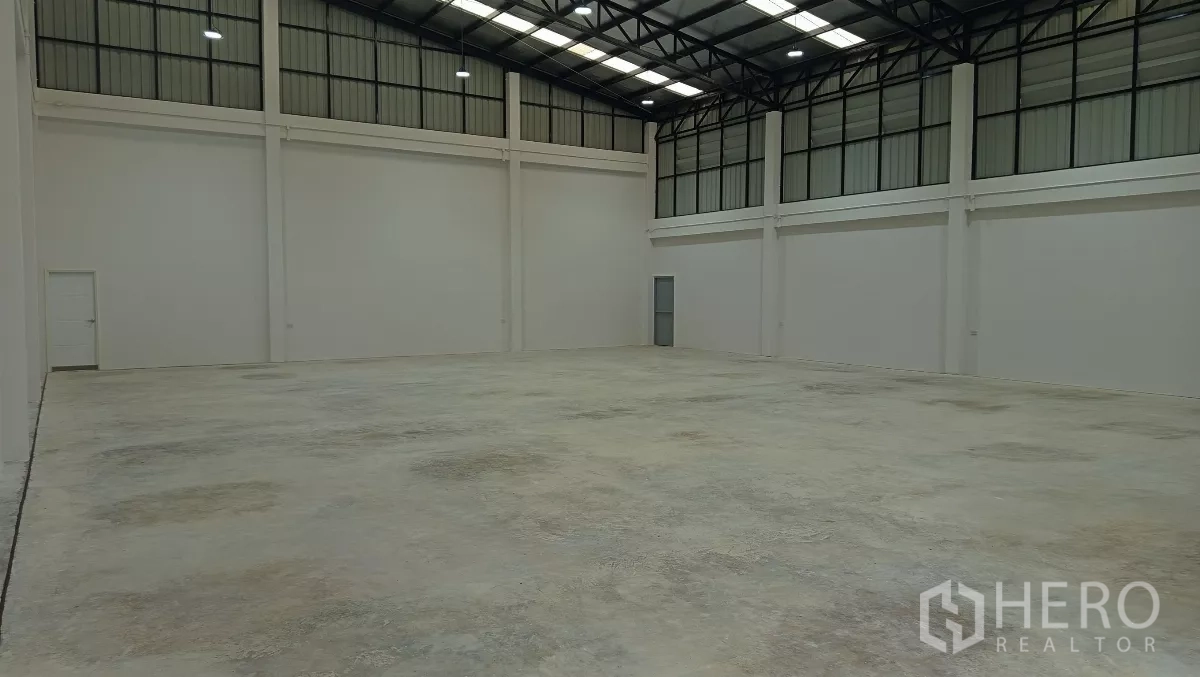 Warehouse for rent or sale in Lam Luk Ka, Pathum Thani - High-clearance warehouse hall with steel truss roof and polished concrete floor.
