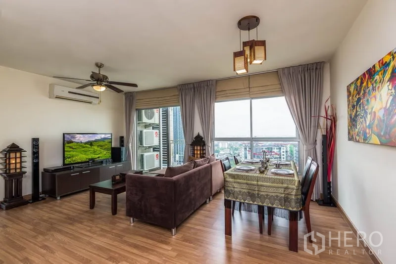Condominium for rent in Bang Na, Bangkok - Bright living and dining area with ceiling fan, large windows, and open city views.