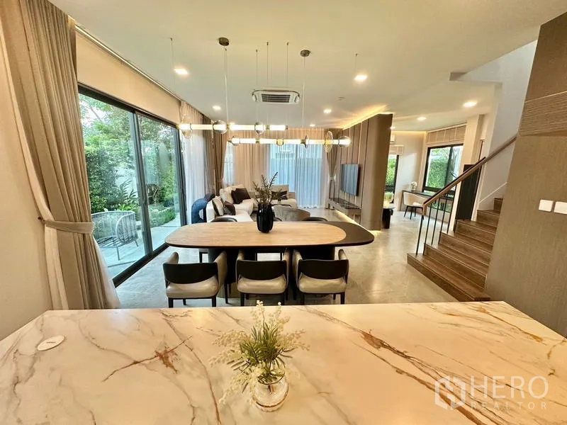 Detached House for rent in Samut Prakan - Kitchen island view toward dining and living spaces with pendant lighting.