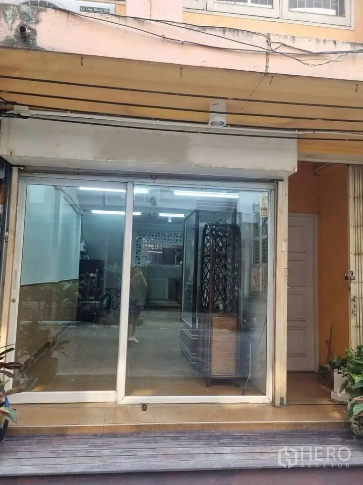 Shophouse for rent in Phra Khanong, Bangkok - Street-level glass storefront with sliding doors revealing the tiled interior.