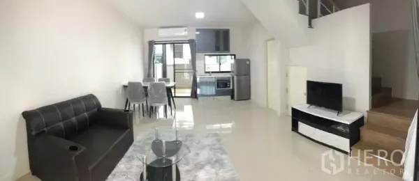 联排别墅 出租或出售在Prawet, Bangkok - 明亮的开放式客餐厅与厨房，配沙发、电视、餐桌和楼梯。