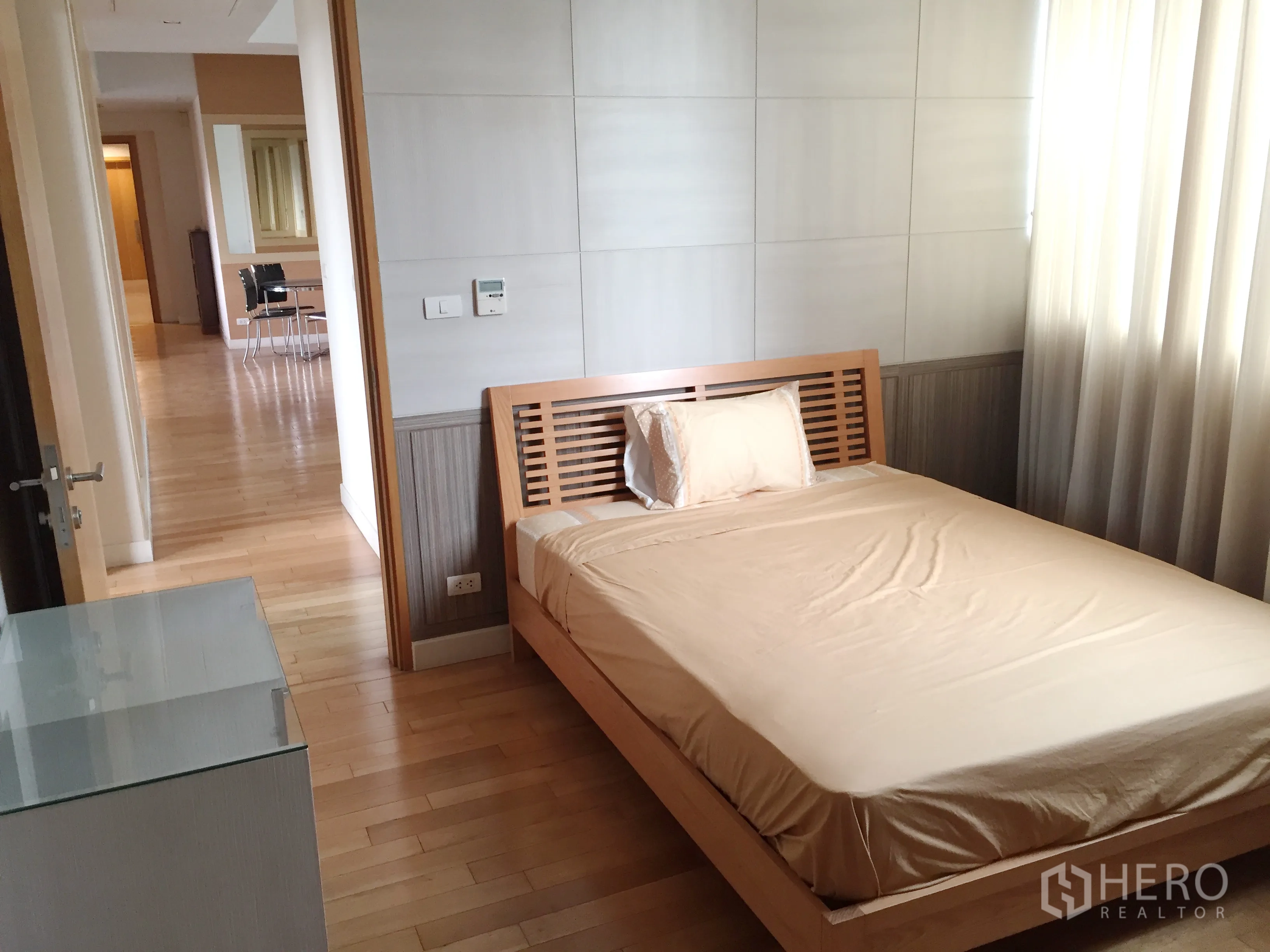 Condominium for rent in Khlong Toei, Bangkok - Second bedroom with wooden bedframe, floor-to-ceiling curtains and view toward the open hallway.