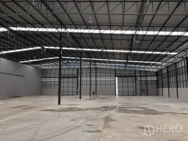 Warehouse for rent in Lat Krabang, Bangkok - Spacious warehouse interior in Lat Krabang, Bangkok with high steel-truss roof, skylight panels, wide concrete floor, and large sliding doors.