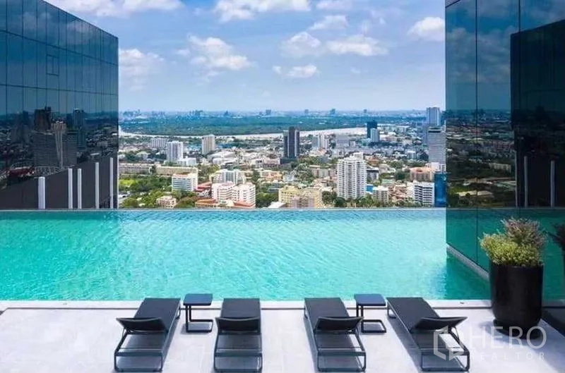 公寓 出租在Sathon, Bangkok - 无边泳池平台，躺椅与城市景观。