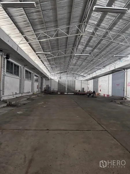 Warehouse for rent in Mueang Samut Prakan, Samut Prakan - Long covered loading area with concrete floor, skylights and truck access.