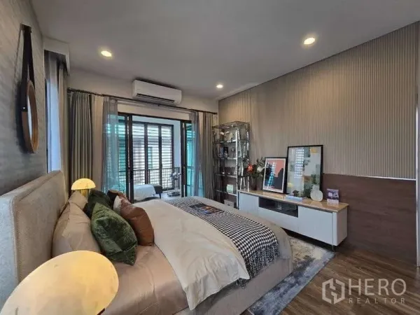 บ้าน ให้เช่าในBang Kapi, Bangkok - มุมห้องนอนใหญ่พร้อมผนังตกแต่ง ทีวีคอนโซล และประตูสไลด์สู่ระเบียง