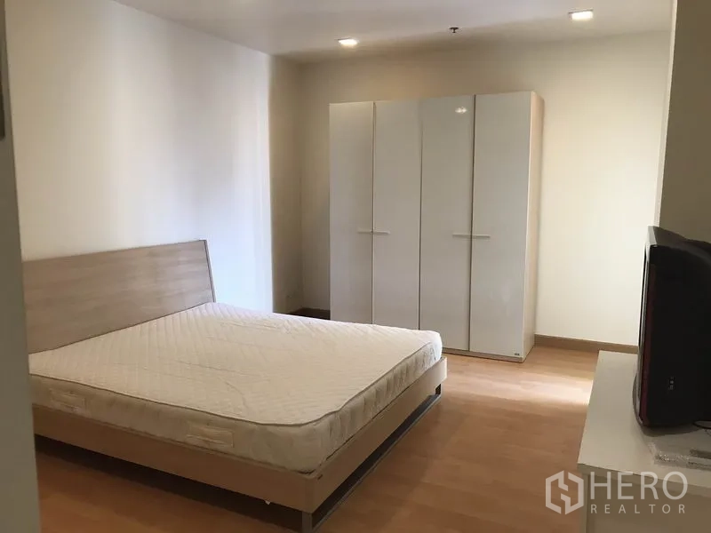 Condominium for rent in Khlong Toei, Bangkok - Bedroom featuring a bed and glossy white wardrobe on wood flooring.