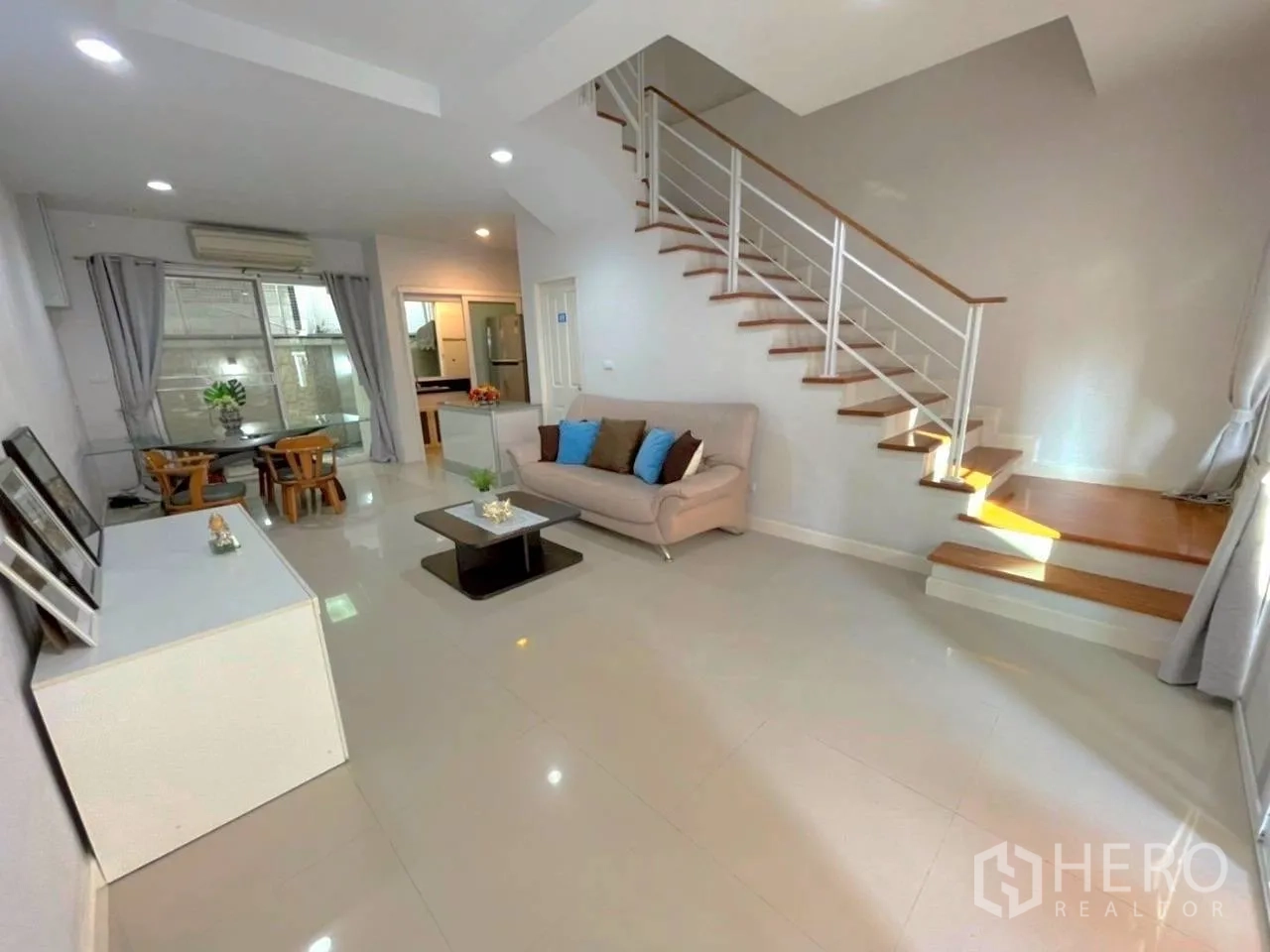 Townhouse for rent in Bang Kho Laem, Bangkok - Wide living area with sofa, coffee tables and stairs under recessed lighting.