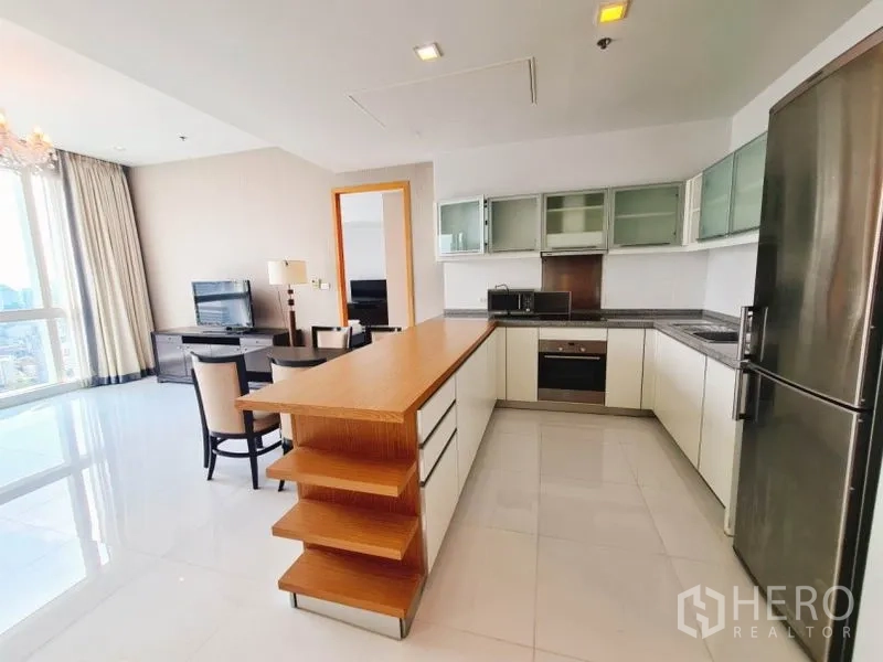 Condominium for rent in Khlong Toei, Bangkok - Modern U-shaped kitchen with wood-topped island, stainless appliances and fridge.