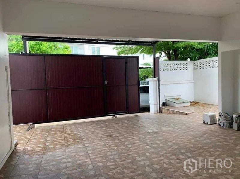 Detached House for sale in Sai Mai, Bangkok - Covered carport with patterned tiles and a sliding wooden gate.