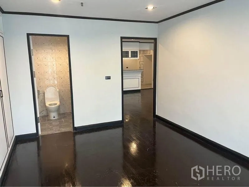 Condominium for rent or sale in Watthana, Bangkok - Bedroom with en-suite bathroom door and view toward kitchen.