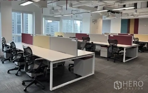 สำนักงาน ให้เช่า - โซนทำงานสว่าง โปร่ง มีโต๊ะแบบกั้น แผ่นพรม และวิวสกายไลน์ผ่านหน้าต่างบานใหญ่