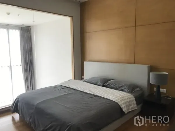 公寓 出租在Khlong Toei, Bangkok - 明亮卧室，木质特色墙，软包床，床头柜与窗帘大窗。
