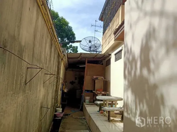 บ้าน ขายในBang Na, Bangkok - ลานด้านข้างแคบ พื้นกระเบื้อง ชุดโต๊ะหินอ่อน และจานดาวเทียมข้างบ้านสองชั้น