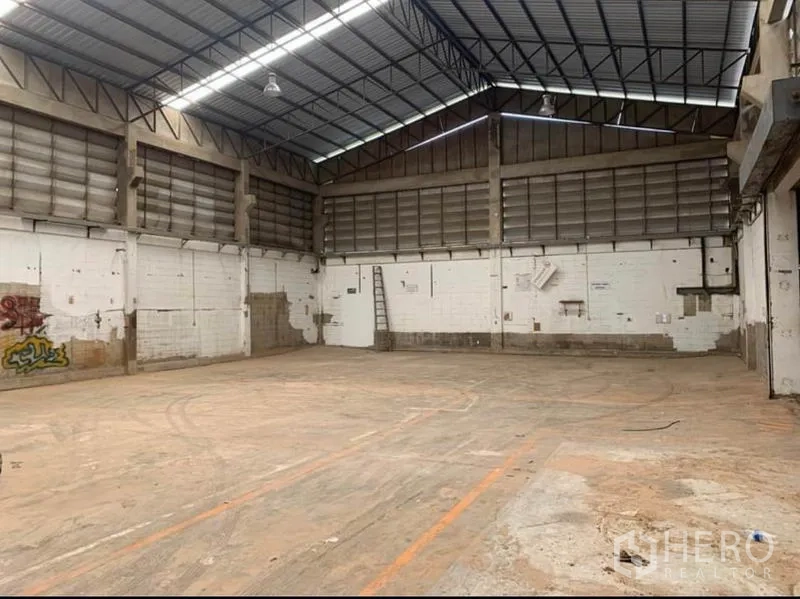 Warehouse for rent in Samut Prakan - Large clear-span warehouse bay with metal roof and marked loading zones.