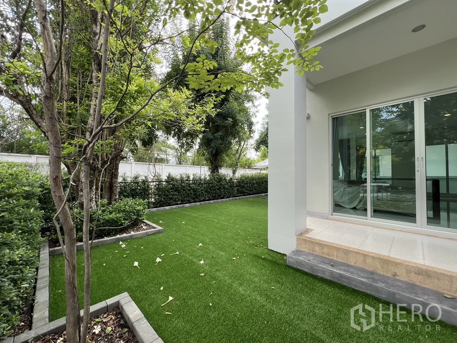 Detached House for rent in Saphan Sung, Bangkok - Backyard lawn with artificial grass beside sliding glass doors.