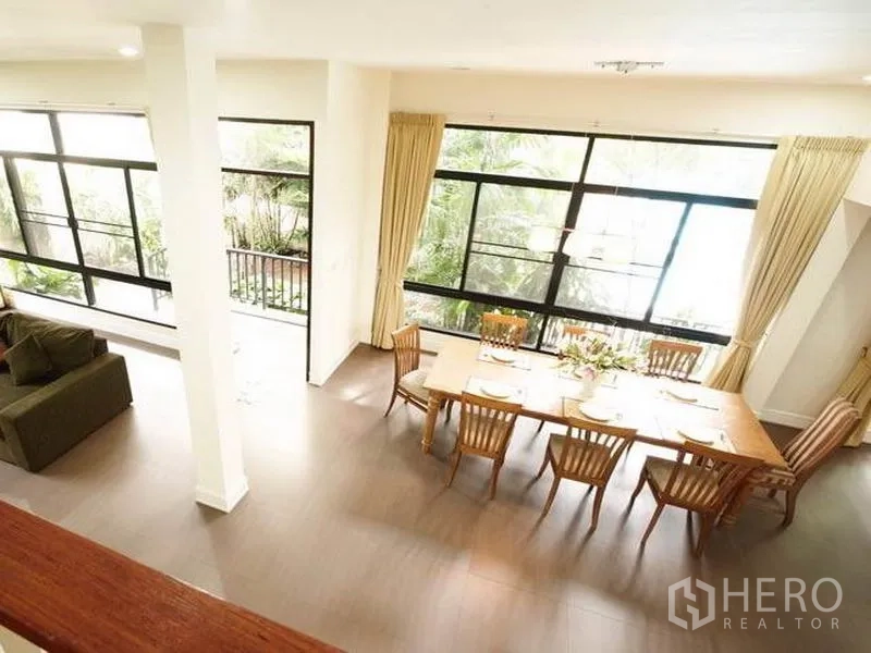 Detached House for rent in Khlong Toei, Bangkok - Dining room view with full-height windows overlooking the garden
