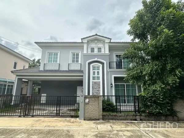 Detached House for sale in Bang Khen, Bangkok - Front facade of a two-storey grey detached house with gated driveway and small balconies.