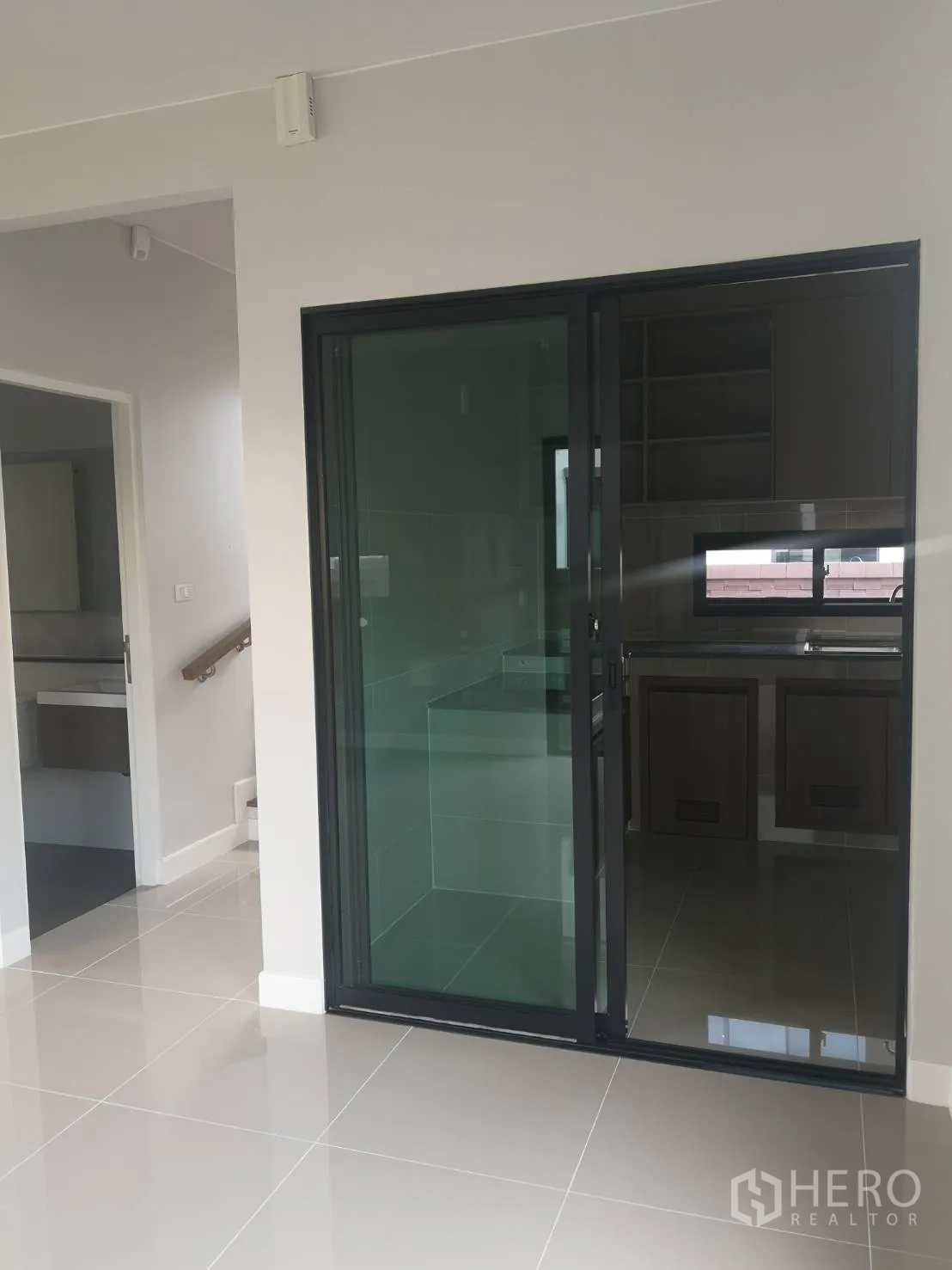 Detached House for sale in Lam Luk Ka, Pathum Thani - Dining area adjoining an enclosed kitchen behind dark-framed sliding glass doors.
