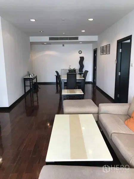 Condominium for rent in Khlong Toei, Bangkok - Open-plan lounge with polished wood floors leading to a dining area.