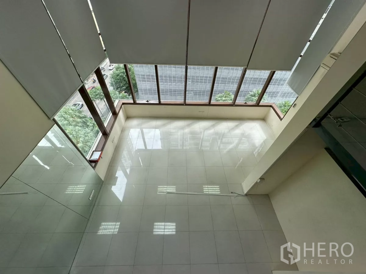 办公空间 出租在Khlong Toei, Bangkok - 自上而下俯视挑高大厅，整面落地窗与街景绿树。