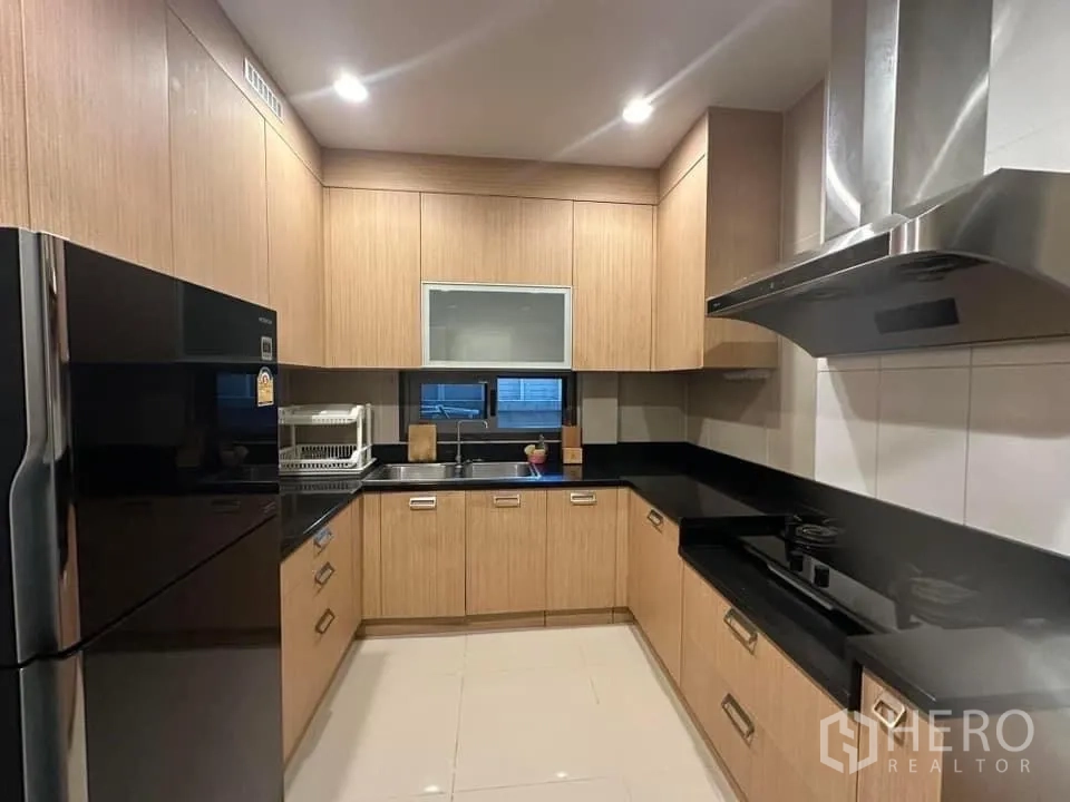 Detached House for rent in Bang Kapi, Bangkok - Separate Thai kitchen with wood cabinets, black countertops and a large cooker hood.