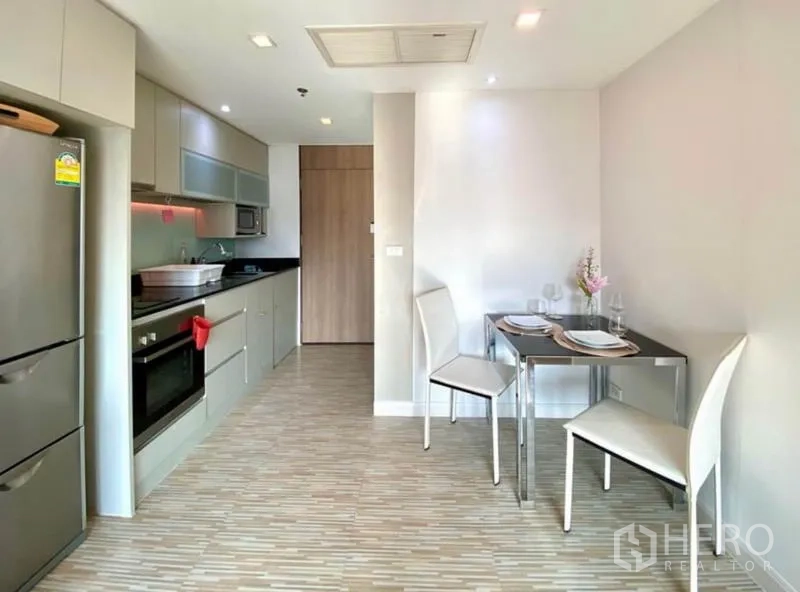 Condominium for rent in Khlong Toei, Bangkok - Open-plan kitchen with oven, microwave, ample cabinets, and an adjacent dining area.
