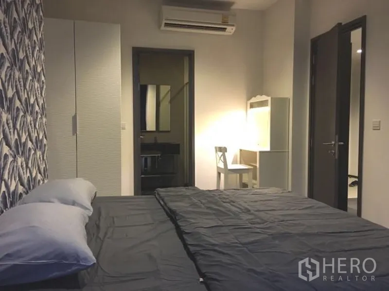 公寓 出租在Watthana, Bangkok - 卧室内可见衣柜、梳妆台与通往浴室的门，灯光柔和。