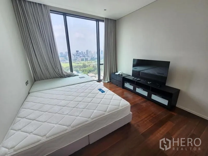 Condominium for sale - Second bedroom featuring twin mattresses, TV console, and full-height window with skyline view.