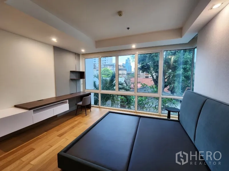 Condominium for rent in Khlong Toei, Bangkok - Bedroom with panoramic windows, built-in desk and platform bed base.