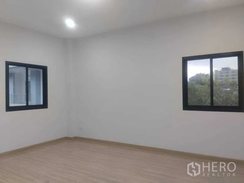 Detached House for sale in Phra Khanong, Bangkok - Bedroom with two windows and wood-look floors offering garden views.