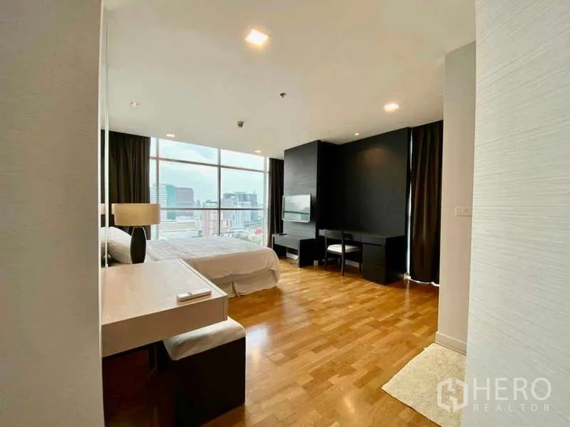 Condominium for rent or sale in Sathon, Bangkok - Master bedroom with desk and full-height windows overlooking the Bangkok skyline.