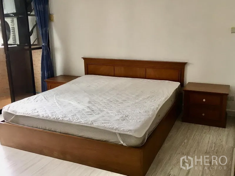公寓 出租在Watthana, Bangkok - 主卧配木床与床头柜，推拉门连接阳台。