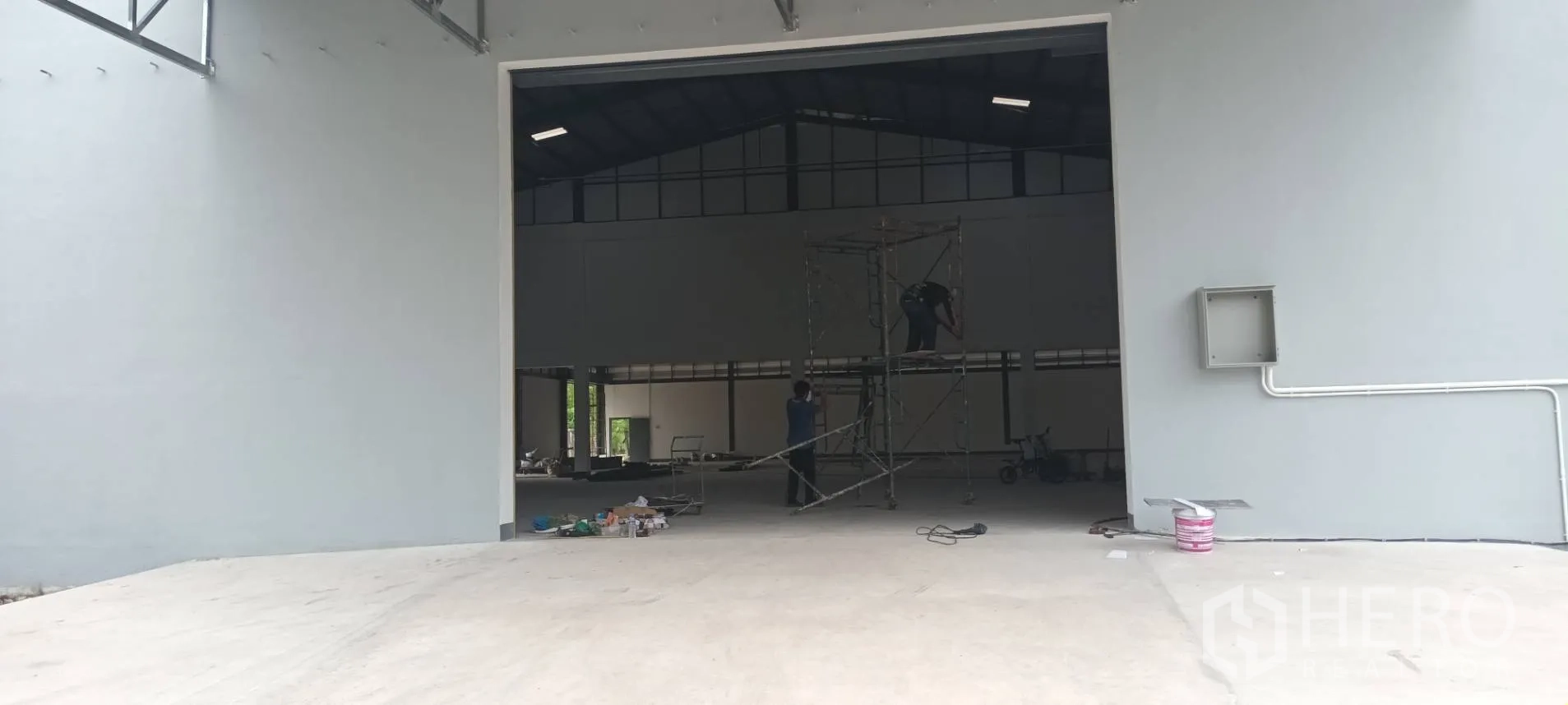 Warehouse for rent in Phra Pradaeng, Samut Prakan - Large warehouse doorway with concrete apron leading into a high-ceiling interior under final touch-ups.