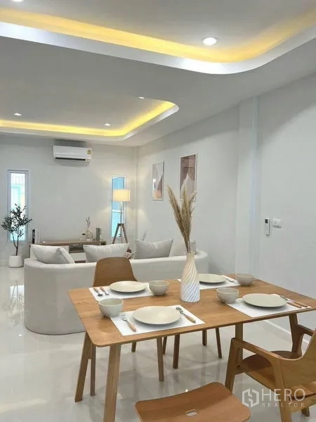 Townhouse for sale in Khlong Toei, Bangkok - Dining zone looking toward bright living room with drop‑ceiling lighting and glossy floors.