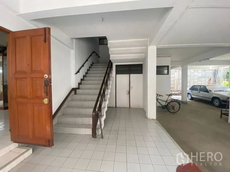 Home Office for rent in Khlong Toei, Bangkok - Interior foyer showing a tiled staircase and adjacent carport area.