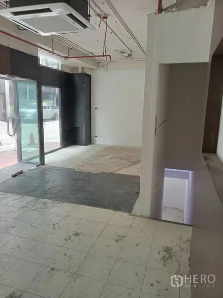 Retail Space for rent in Watthana, Bangkok - Open-plan shop space beside street-facing glass doors with mixed flooring and ceiling ductwork.
