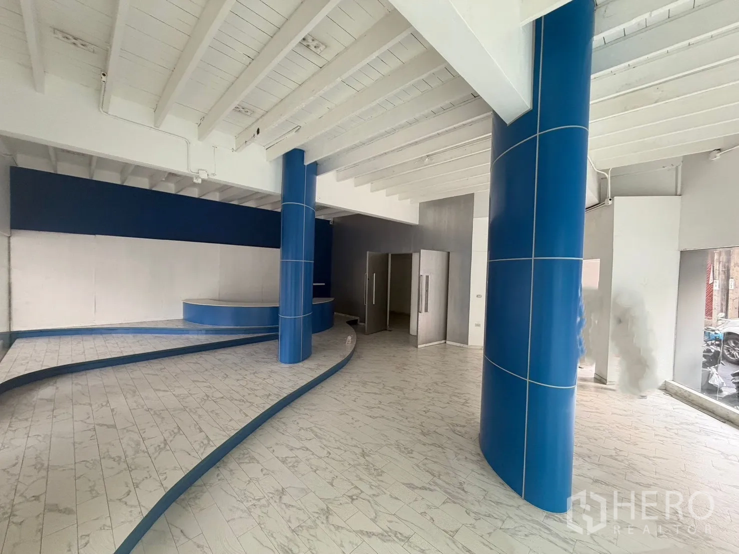 店屋 for rent in Watthana, Bangkok - 宽敞展示区，蓝色立柱与弧形展示平台。
