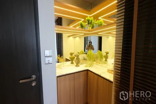 คอนโด ให้เช่า - มุมตกแต่งด้วยผนังกระจก ไฟเส้น LED เพดาน และท็อปหินอ่อนประดับต้นไม้