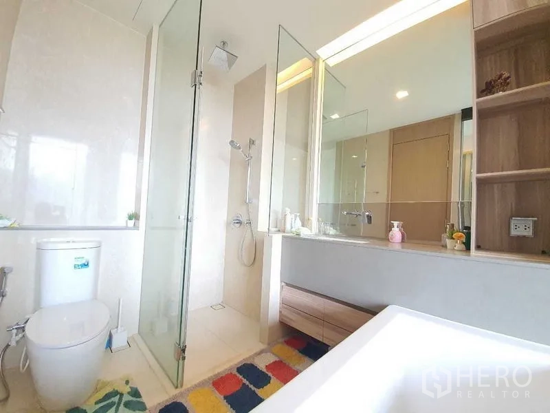 公寓 出租或出售在Watthana, Bangkok - 现代浴室，玻璃淋浴间、顶喷花洒与大镜面洗手台，色调素雅。