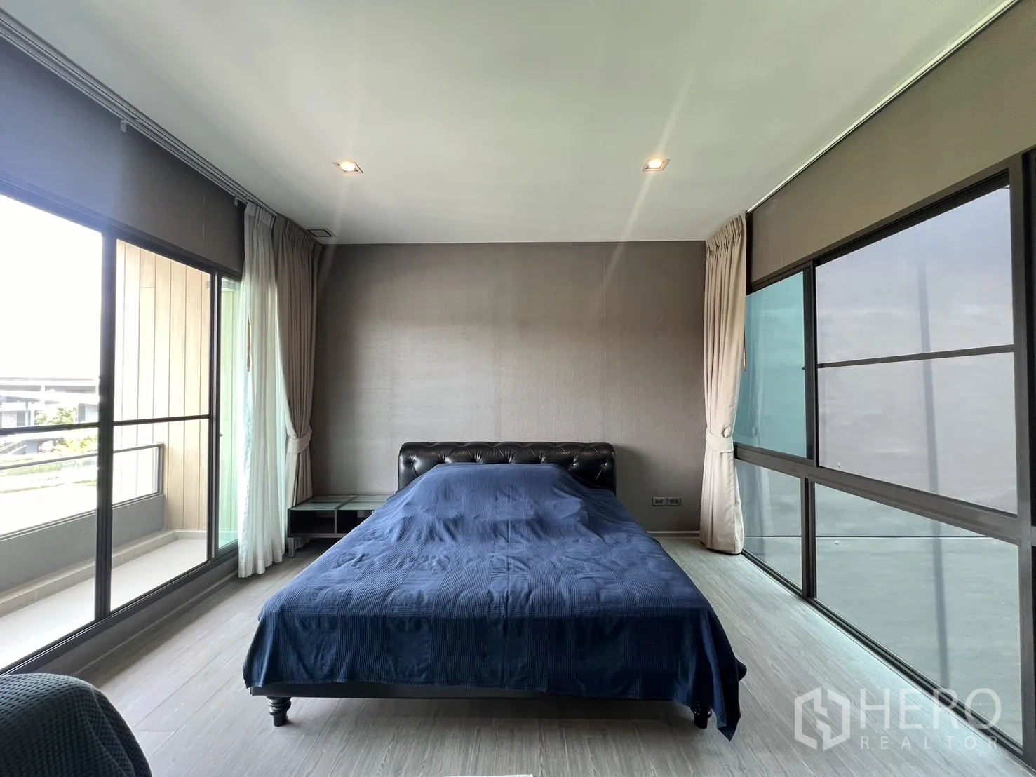Townhouse for rent in Lat Phrao, Bangkok - Master bedroom alternate angle with wide windows on two sides and curtains.